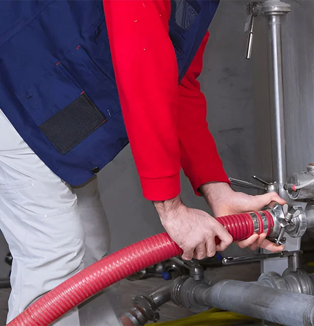 Close-up of a technician coupling a hose to a boiler connection